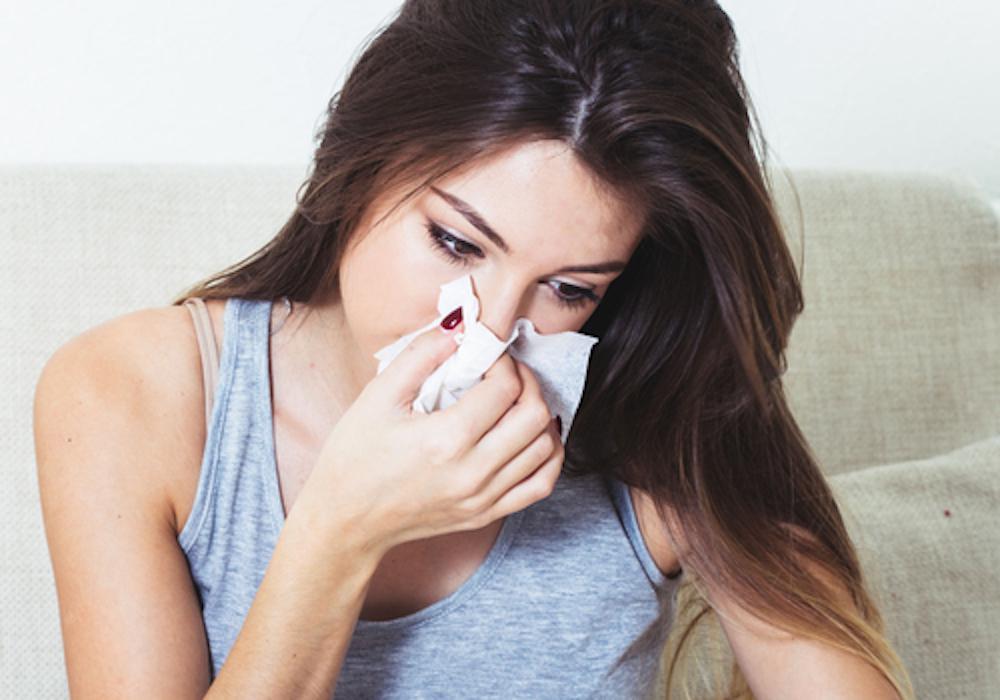 Woman sneezing into a tissue