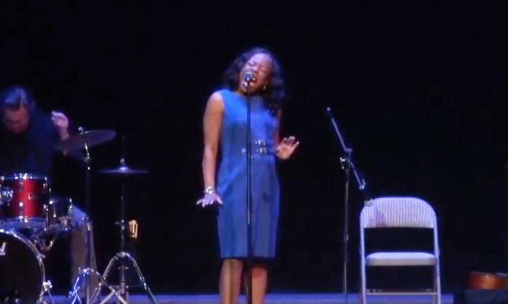 Woman singing on stage with a band