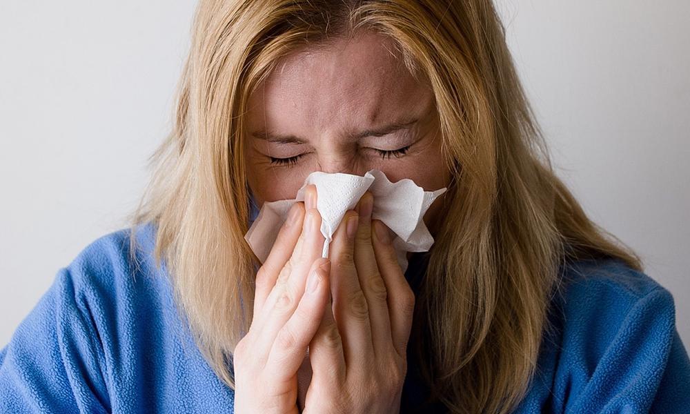 Woman sneezing into a tissue