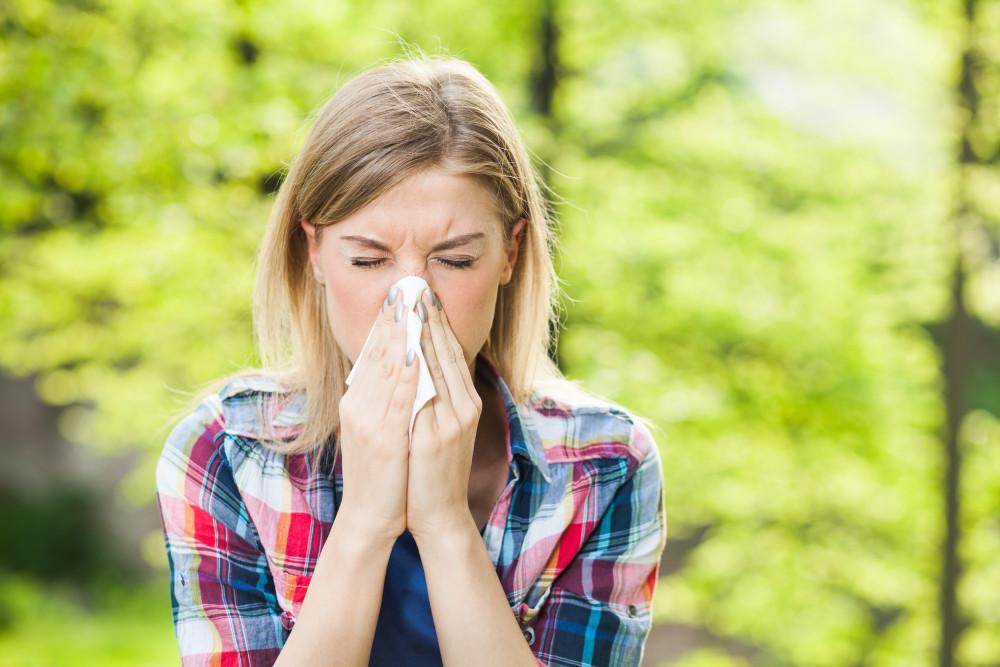 Woman sneezing into a tissue