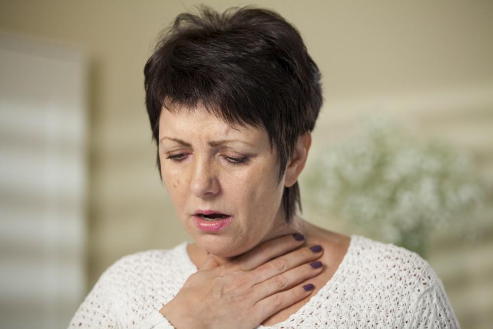 Woman holding her throat coughing