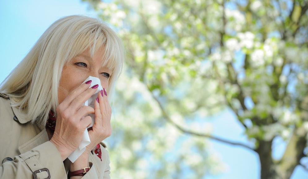 Woman sneezing into a tissue